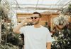 man in white crew-neck shirt wearing sunglasses standing near plants