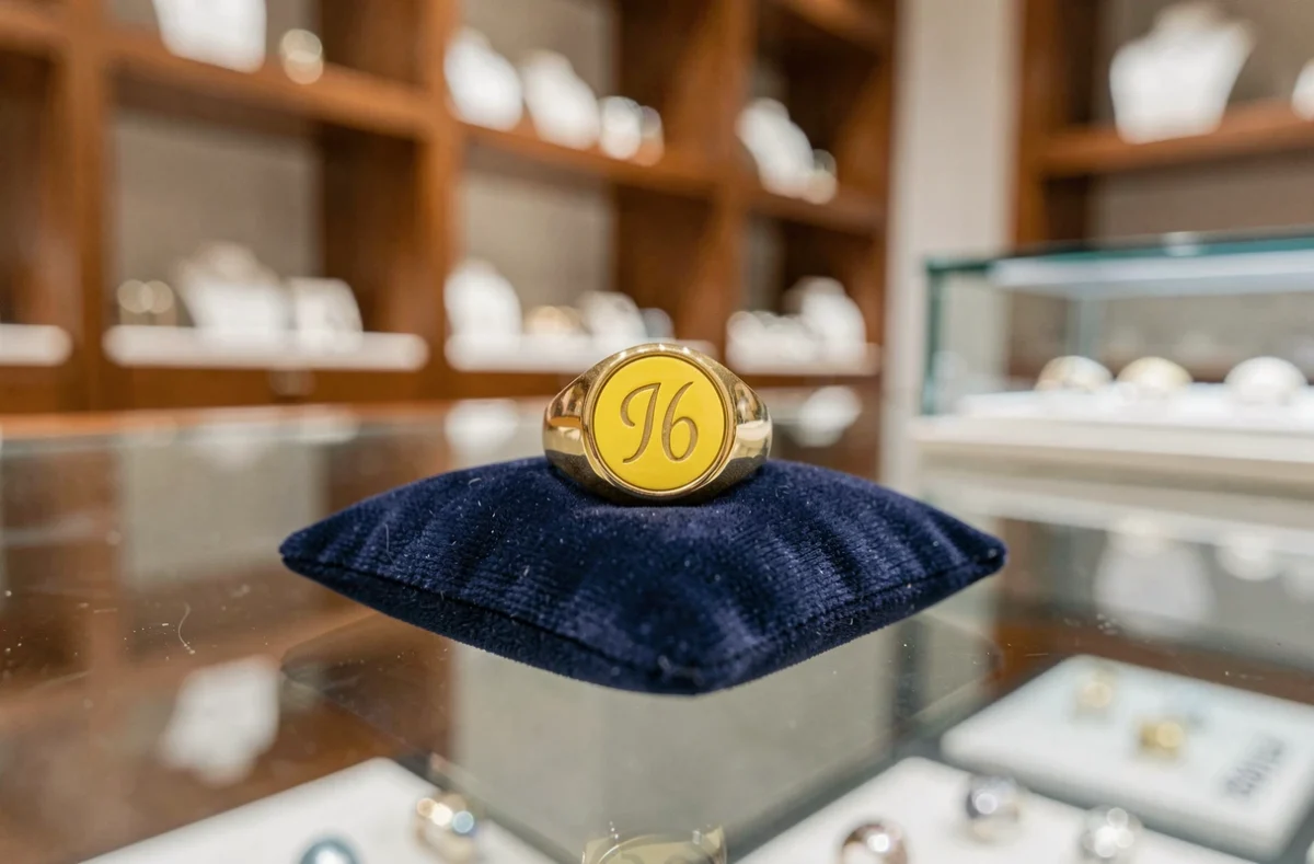 Bague chevalière en or posée sur un coussin en velours bleu marine dans une vitrine de bijouterie moderne