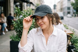 Jeune femme en blanc et casquette dans un café urbain