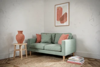 Coin salon parisien en vert d'eau et corail avec canapé en lin, vase en céramique terracotta et parquet point de Hongrie